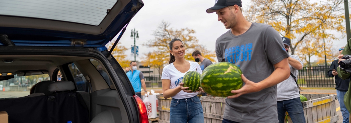 NFL Player Jared Goff holds fresh fruit as he loads a vehicle during a food donation event in Detroit